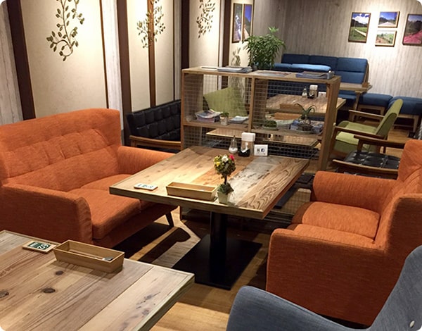 画像：室内にソファーとテーブルが複数あり。青とオレンジのゆったり座れるソファになっている。