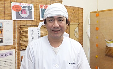 画像：荒木豆腐店の職人さんが、作業着で笑みを浮かべています。